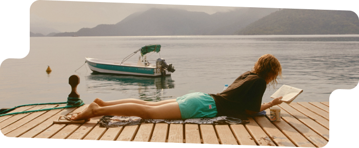 A person reading on a dock by the water